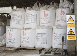 Danger fertiliser store oxidising agent sign Ammonia Nitrate bags in barn, Suffolk, England, United