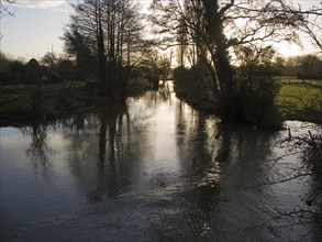 Winter landscape trees and water with low sun in sky River Deben, Ufford, Suffolk, England, United