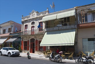 Traditional buildings on a sunny street with parked cars and motorbikes, Museum of Silk Art,