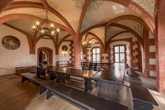 Court parlour with cross vaulting, chandelier, solid wooden tables and benches, medieval knight's