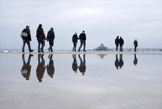 Walkers reflected in the water on the beach in Heringsdorf, Usedom Island, 21/09/2019