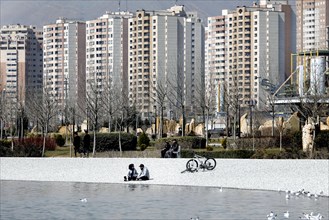 A young couple sits on the beach of Lake Chitgar in Tehran, Iran. Lake Chitgar is a man-made lake