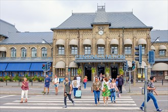 Railway station in Gothenburg with people crossing a city street at the pedestrian crossing,