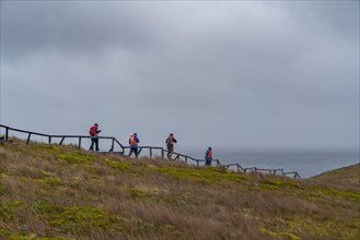 Passengers of the cruise ship Stella Australis in life jackets hike in storm and rain to Cape Horn,