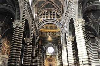 The nave of the cathedral with its black and white striped marble columns, cross and round arches,