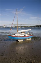 Sailing boat in mud at low tide with the Orwell Bridge in the background, River Orwell estuary,