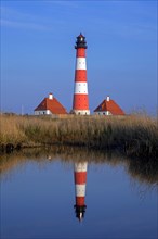 Lighthouse Westerheversand reflected in pond at Westerhever at dusk, Peninsula of Eiderstedt,
