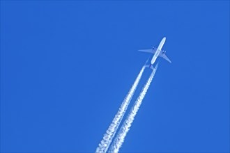 Flying twin-engine jet airliner, aircraft, plane from the airline Kuwait Airways showing contrails,