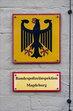 Yellow and red sign with Federal Police Inspectorate and an eagle on the wall of a building,