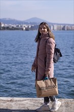 Young woman, coat, shopping bag, shopping, sea, old harbour, Thessaloniki, Macedonia, Greece,