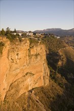 Historic buildings perched on sheer cliff top in Ronda, Spain, Europe