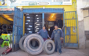 Peruvian couple, 38 and 45 years old, showing tyres from their tyre workshop, Palccoyo, Checacupe