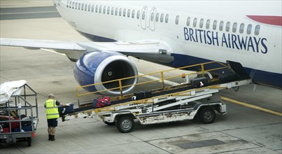 Baggage handler loading luggage onto British Airways plane at gatwick airport, London, England,