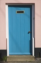 Blue house door with pink surround seen in Aldeburgh, Suffolk, England, United Kingdom, Europe