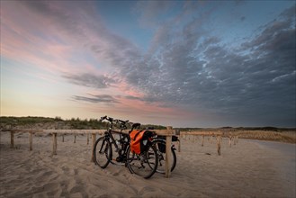 Two bicycles on the beach during a picturesque sunset with dramatic clouds, Texel, Netherlands
