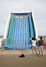 Children playing on giant inflated slide seaside attraction, Great Yarmouth, Norfolk, England