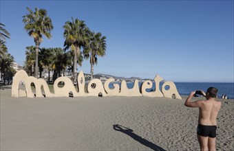 A man takes a photo of a large Malagueta logo. Malagueta is the name of the beach in Malaga, on the