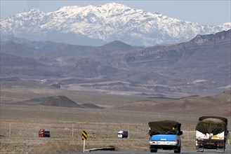 Truck on a motorway in the central desert of Iran, snow-capped mountains can be seen in the