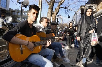 Young Iranian street musicians with guitars in Arak, Iran, woman with chador on 16 March 2019.