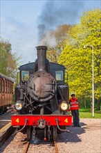 Old steam locomotive at a railway station with a driver outside the locomotive, Sweden, Europe