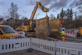 Road construction site: Excavator with a civil engineering safety device on the hook, Eckental,