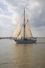 Historic wooden sailing yacht boat in full sail at the mouth of River Deben, Suffolk, England,