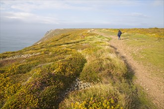 Woman wearing kagoule walking along the South West coast path at St Agnes head, Cornwall, England,