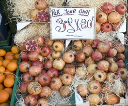 Pomegranates for sale on market stall three for one pound twenty pence