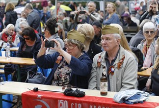 A man and a woman wear caps from Russian uniforms on the 74th anniversary of the victory of Russia