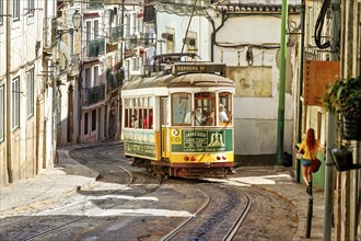 The historic yellow tram winds its way through the historic centre of Lisbon past the old houses of