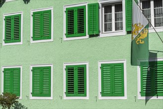 Old town of Dissenhofen on the Rhine, green house, shutters, flag with cantonal coat of arms,