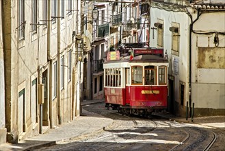 The historic red tram winds its way through Lisbon's historic centre past the old houses of this