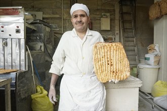Portrait of a baker with freshly baked bread, Tehran, Iran, 09.03.2019, Asia