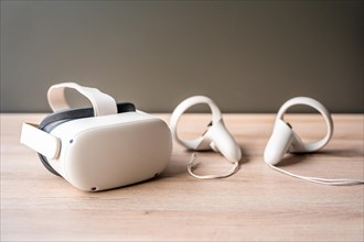Futuristic white virtual reality goggles and earphones on wooden table