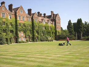 Man mowing grass lawn in courtyard of Selwyn College, University of Cambridge, England, United