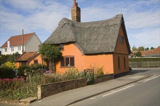 Orange coloured historic thatched building in Hollesley village, Suffolk, England, United Kingdom,