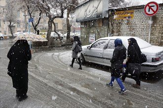 Heavy snowfall in Arak, Iran, woman with chador and umbrella and traditional clothing, 16/03/2019,