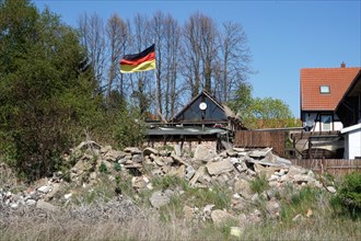 A German flag flutters in front of a pile of rubble on a house, Schoeningen, 22/04/2019