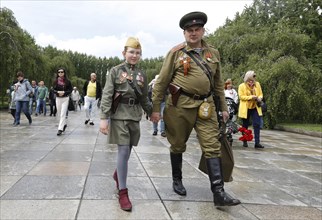 Men in Russian uniforms walk to the Russian memorial in Treptower Park in Berlin on the 74th