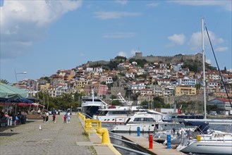 View of a lively harbour promenade with boats, people and a castle on a hill, fortress, old town,