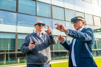 Aged businessman with colleague wearing virtual reality simulator gesturing at financial district