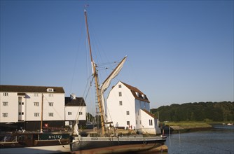 Historic sailing barge and whitewashed buildings of the Tide Mill on the River Deben, Woodbridge,