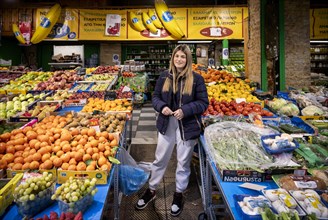 Trader, fruit seller, young woman, posing proudly in front of her market stall, display of fresh