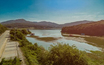 A scenic landscape depicting a serene river winding through mountains under a blue sky, in South