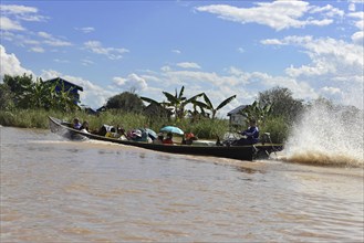 Long passenger boat travelling fast on a river and creating waves, Inle Lake, Myanmar, Asia