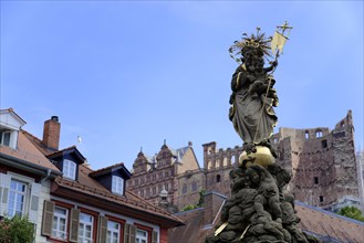 Statue with crown and sceptre, Marienbrunnen, in front of a castle ruin and blue sky, Heidelberg,
