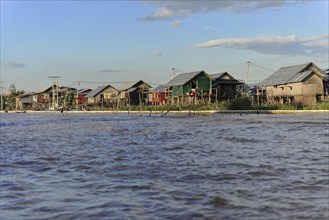 Stilt houses on the edge of a river with golden evening light, Inle Lake, Myanmar, Asia