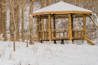 A wooden gazebo covered with snow in a tranquil forest setting, in South Korea