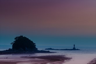 Silhouette of a lighthouse on a tranquil beach under a purple and orange sunset sky, in South Korea