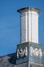 Close-up of a white chimney with decorative elements on a grey roof, Middelburg, Zeeland,